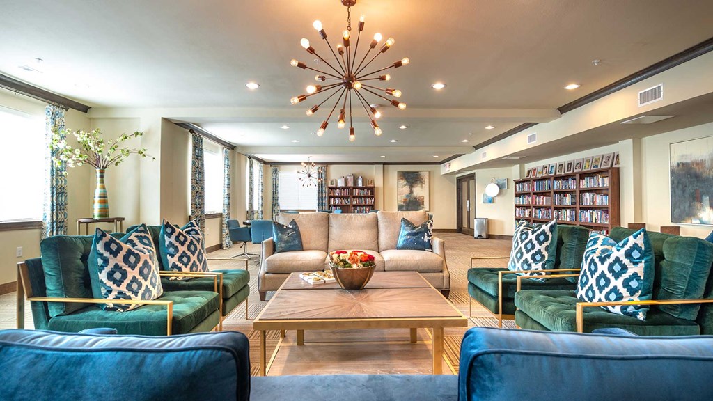 Four plush coaches face other around a large coffee table. There are shelves along the walls with games and more.
