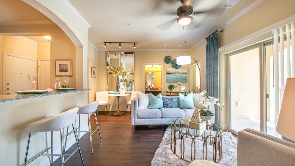 A living room in Bell Tower Reserve. A bar to the kitchen is on the left; a sitting area ahead and a sliding glass door to the patio on the right.
