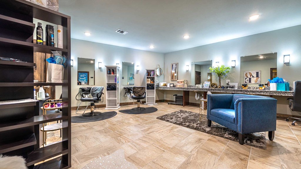 A couple of salon stations are along the wall with a shelf of beauty supplies in the foreground.