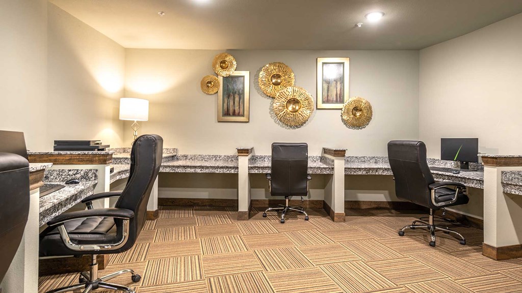 The wall is lined with several built-in desks, each with a large office chair.