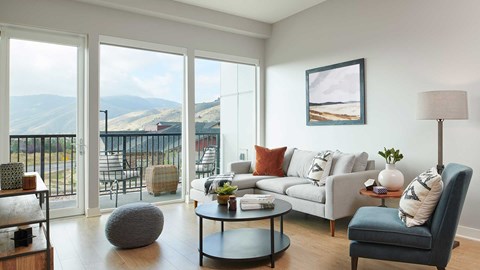 Epoque Golden apartment living room with sofa, large windows, private balcony and foothill views.