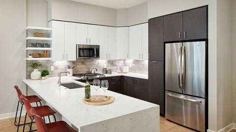 Epoque Golden apartment kitchen with quartz island, stainless-steel appliances, gas range, modern cabinetry and bar seating.