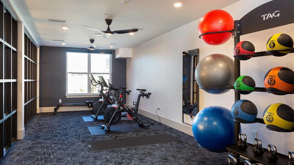 There are mounted bikes ahead, an exercise mirror in the middle and various heavy balls on the right.