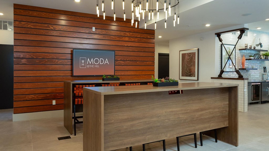 Two wooden bars sit out from the wall that has a large television on it. Off to the right is the catering kitchen.