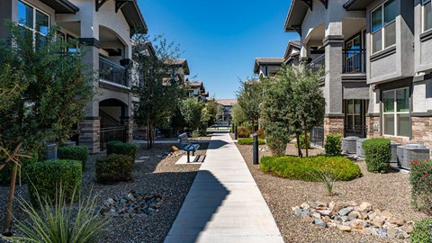 a walkway between two apartment buildings with trees and landscaping