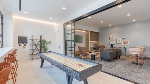 Modern resident entertainment lounge at Tempo at Nine Mile featuring a shuffleboard table, lounge seating, coworking space, and contemporary interior design.