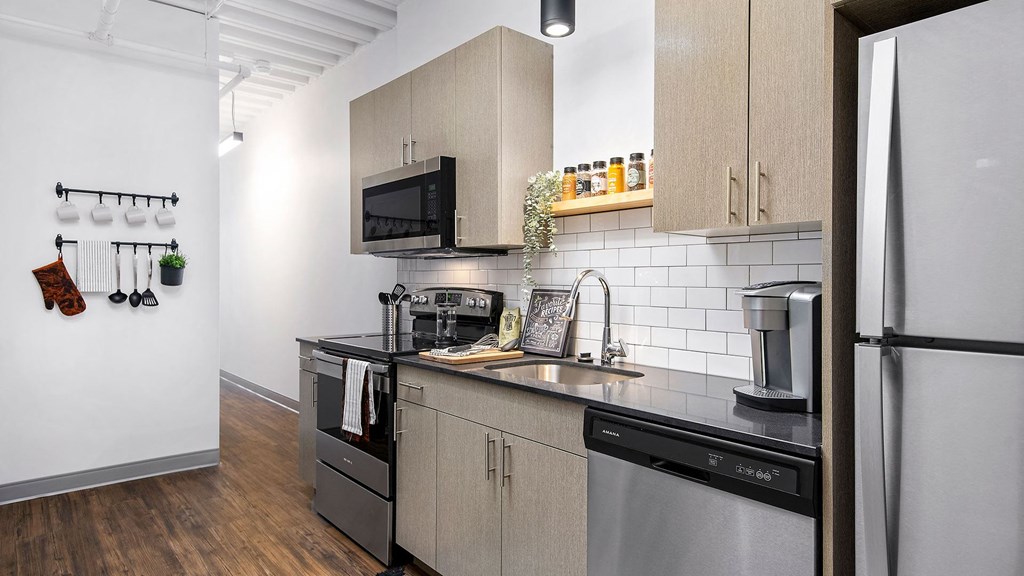 Looking along the kitchen counter in a residence at Wrigleyville lofts. Stainless steel appliances are set along the cabinets.