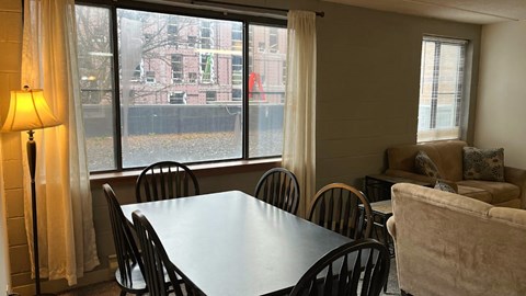 A dining room with a table, chairs, and a lamp.