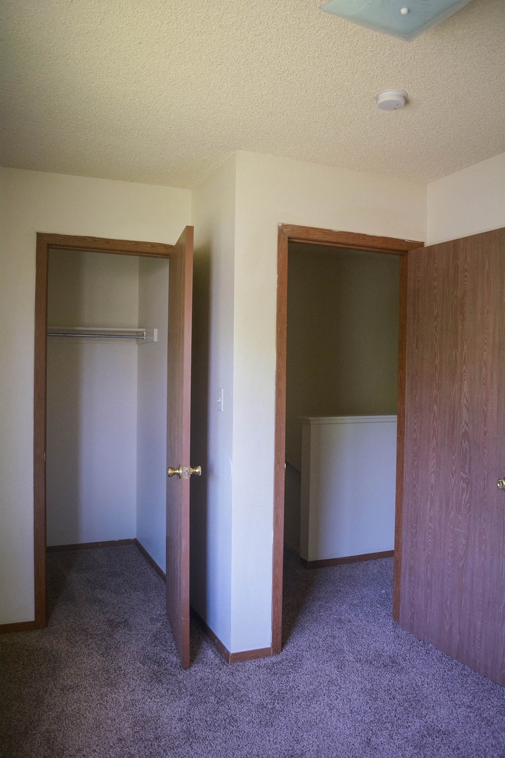 an empty room with a closet and a door to a bedroom