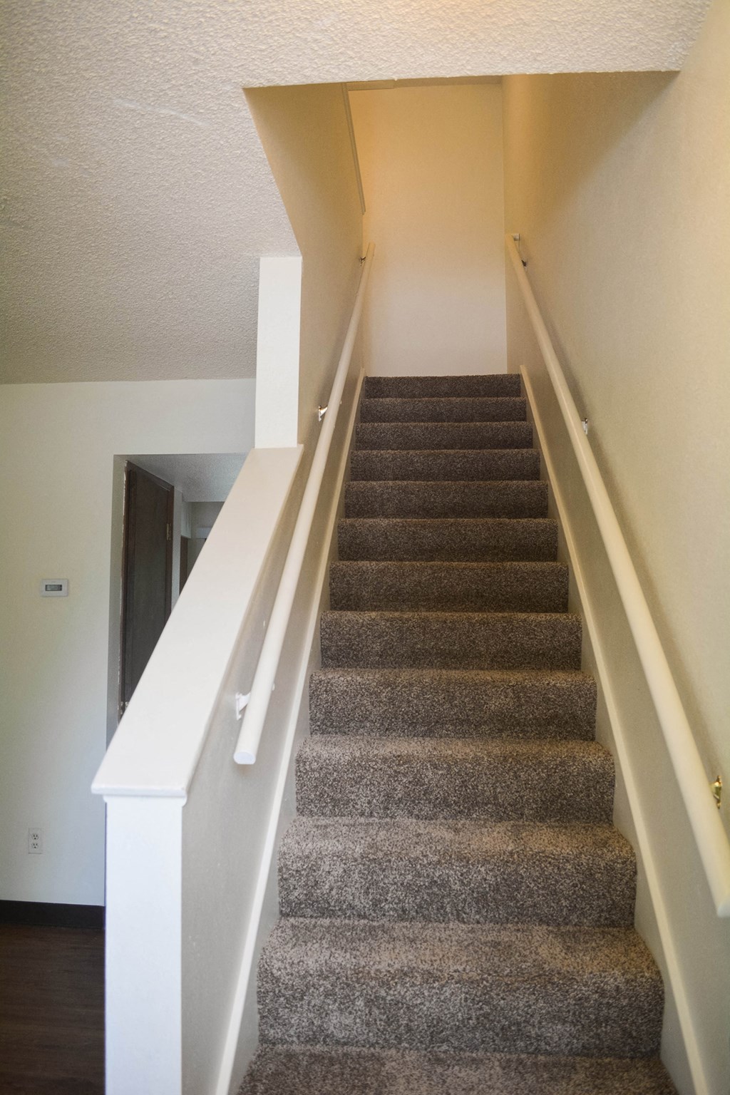 a set of carpeted stairs with white railings and gray carpet on the stairs