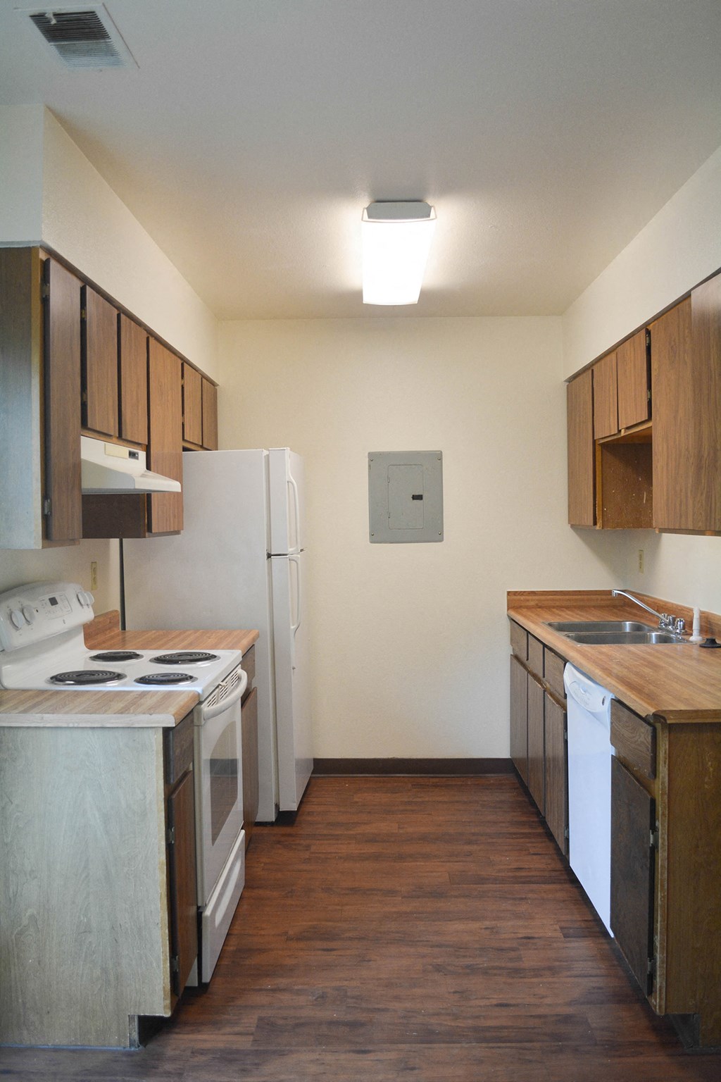 an empty kitchen with white appliances and wooden cabinets