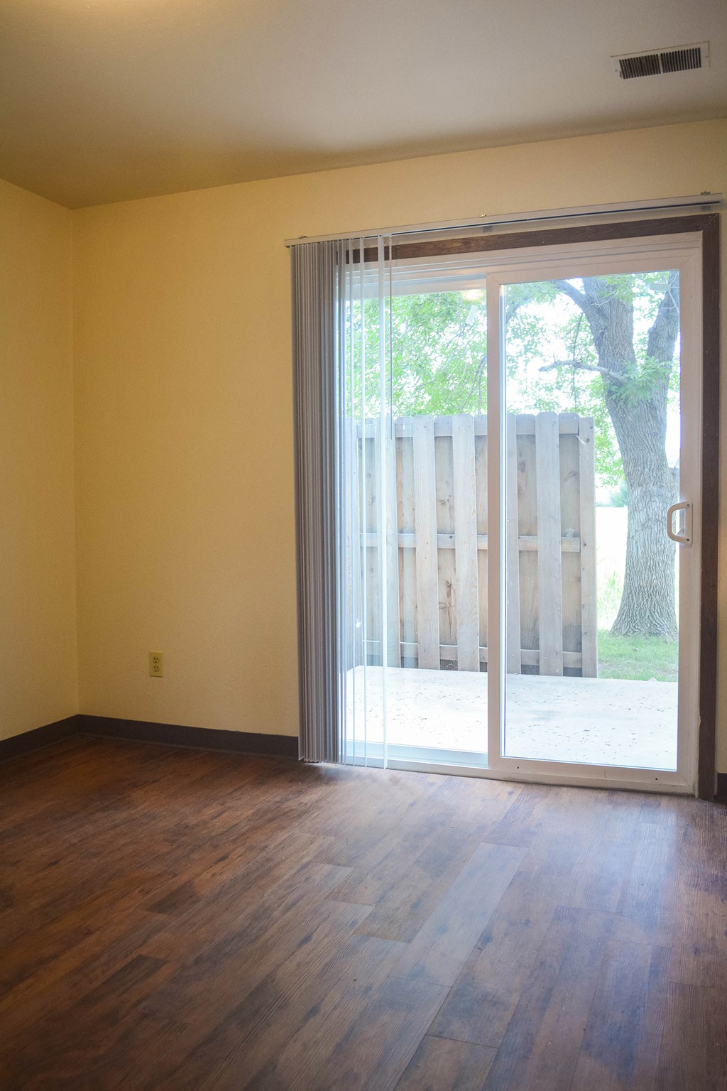an empty living room with a sliding glass door to a yard