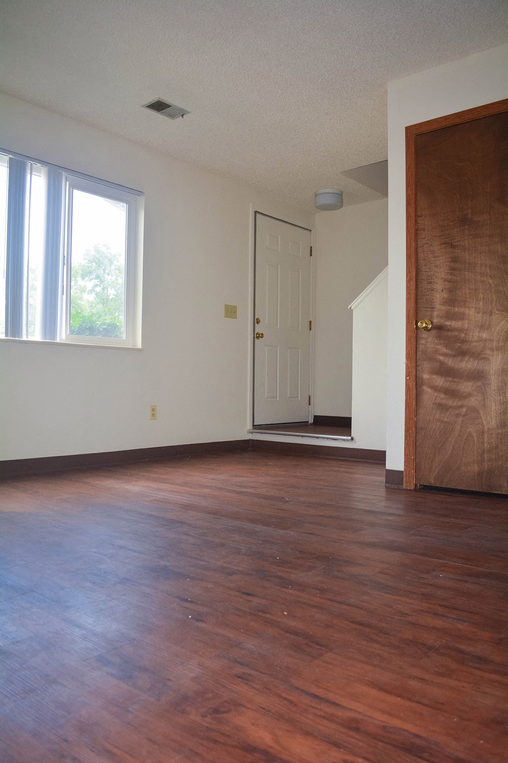 an empty living room with wood floors and a door