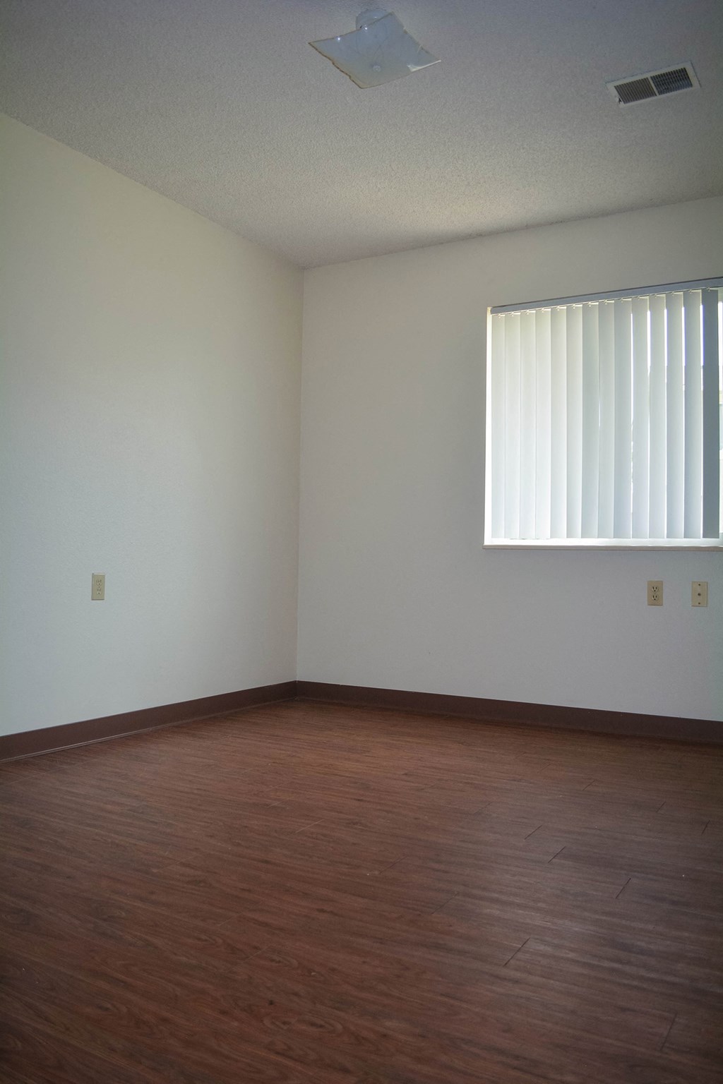 an empty room with wooden floors and a window