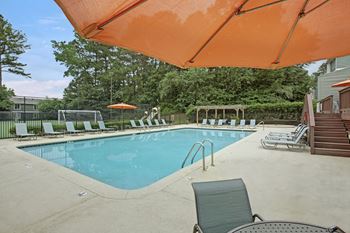 A pool with a blue water and a sun umbrella.