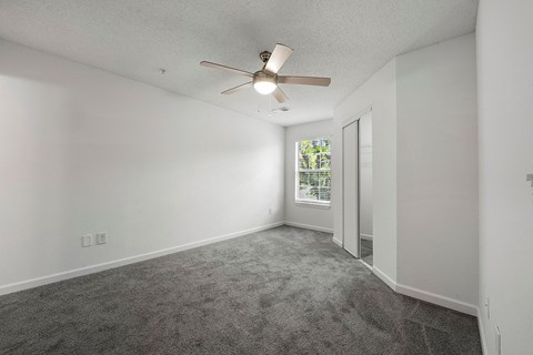A room with a ceiling fan and carpeted floor.