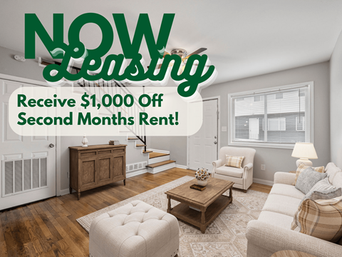 A living room with a large advertisement for "NOW Leasing" offering $1,000 off the second month's rent.