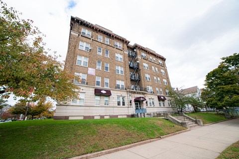 A brown building with a red awning sits on a grassy hill.