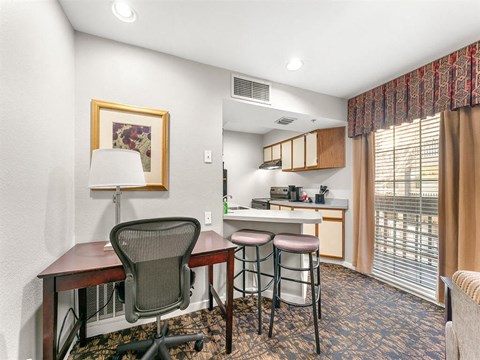 a living room with a kitchen and a table with three stools