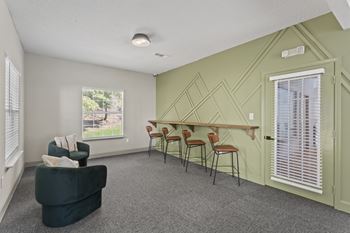A room with a green couch, chairs, and a table with a wooden top.at Eastlake Gardens, Decatur