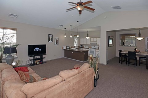 A living room with a couch, television, and a ceiling fan.