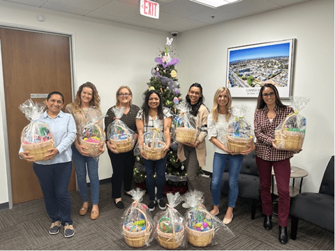 A group of people holding baskets in front of a Christmas tree.