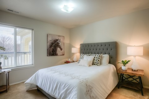 A bedroom with a large bed and a painting of a horse on the wall.