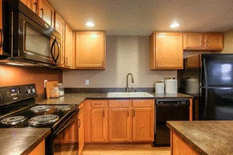 A kitchen with wooden cabinets and black appliances.