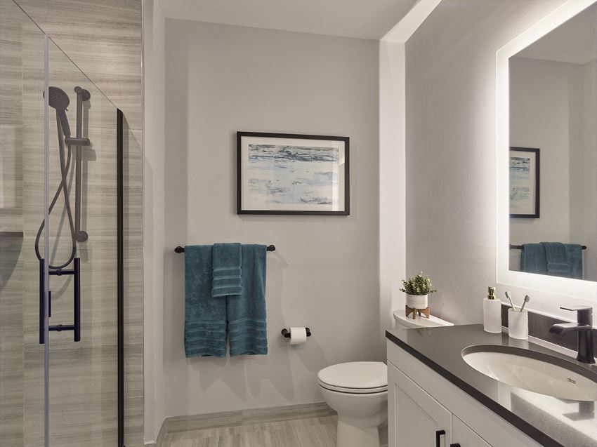 Residences large bathroom with glass shower door, tiled floors, backlit vanity - Photo Gallery