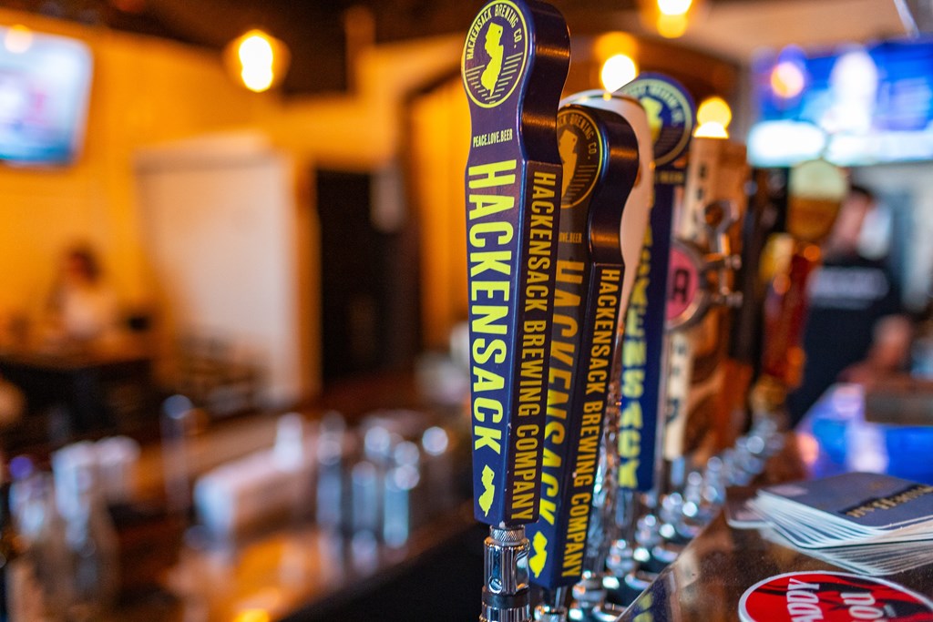 A row of beer taps with the Hackensack Brewing Company logo on them.
