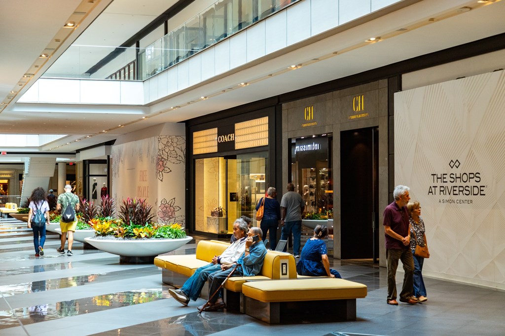 A group of people are sitting on a bench in a shopping mall.