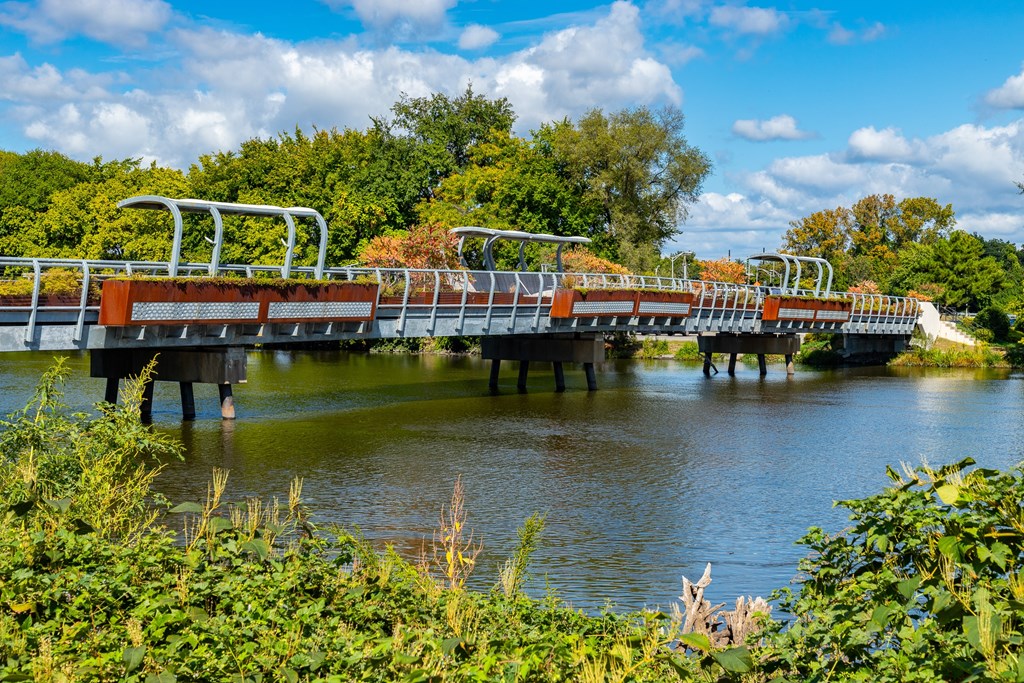 A metal bridge over a body of water with trees in the background.