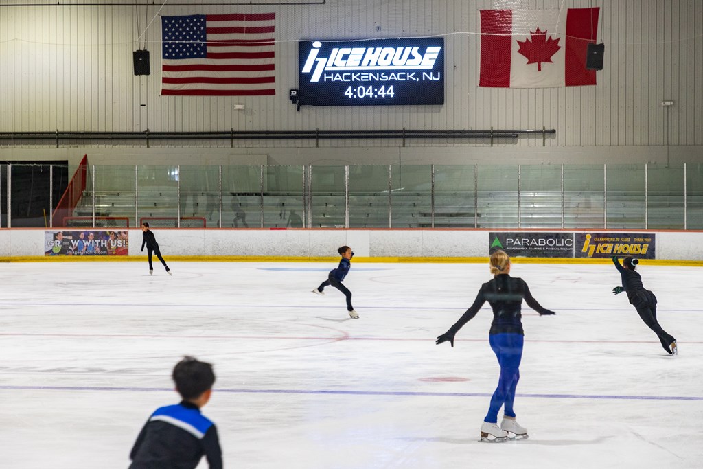 A hockey rink with people playing and an American flag hanging on the wall.