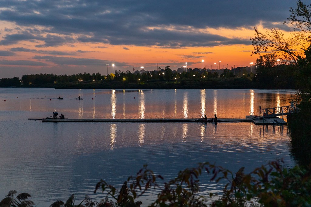 A serene lake with a boat and dock at sunset.