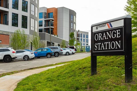 A sign for Orange Station is in front of a grassy area.