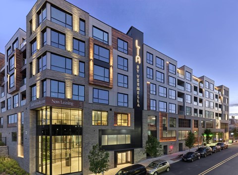 A modern multi-story building with the words "Now Leasing" on the front.