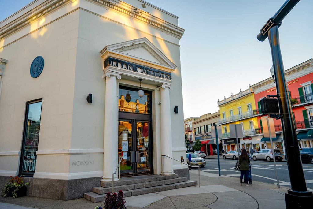 A white building with a blue circular sign on the left side and the text "Jamaican Brewster" above the entrance.