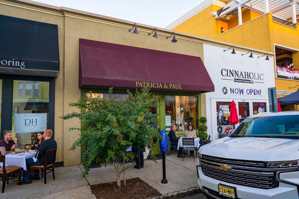 A white truck is parked in front of a Cinnaholic store.