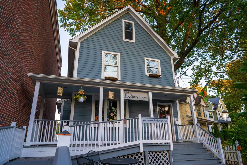 A blue house with a porch and a sign that says "The Popcorn House".