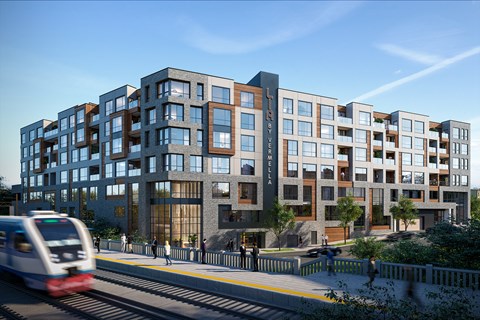 A modern building with a train passing by on the tracks in front.