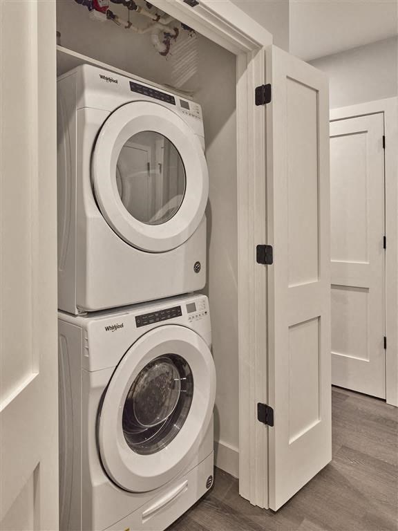 Two white front load washing machines stacked on top of each other in a laundry room.
