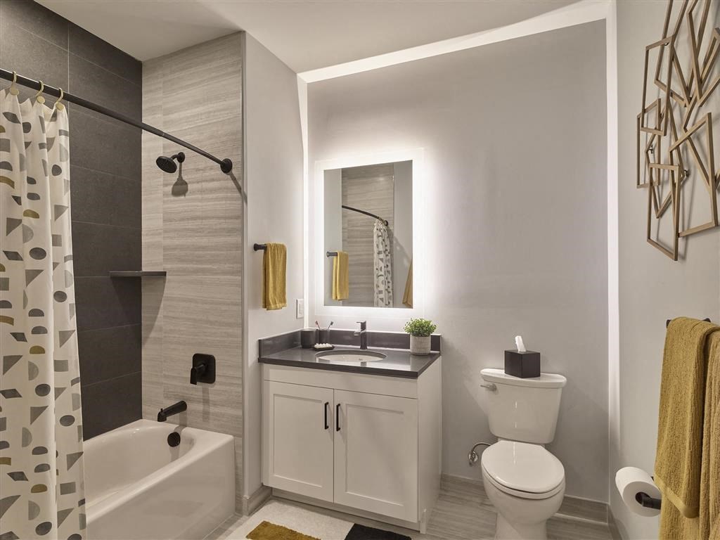 A modern bathroom with a white toilet, sink, and bathtub.