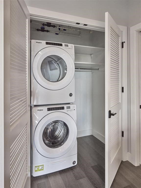 A white dryer and washer are stacked on top of each other in a small laundry room.