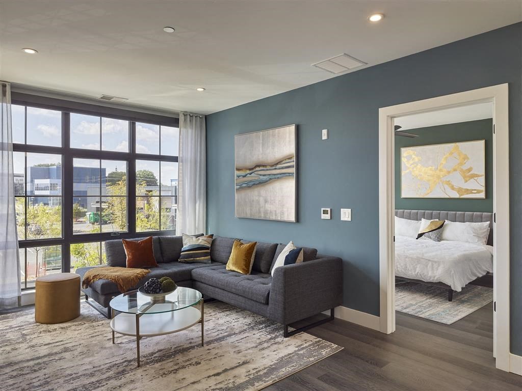 A living room with a grey couch and a glass coffee table.