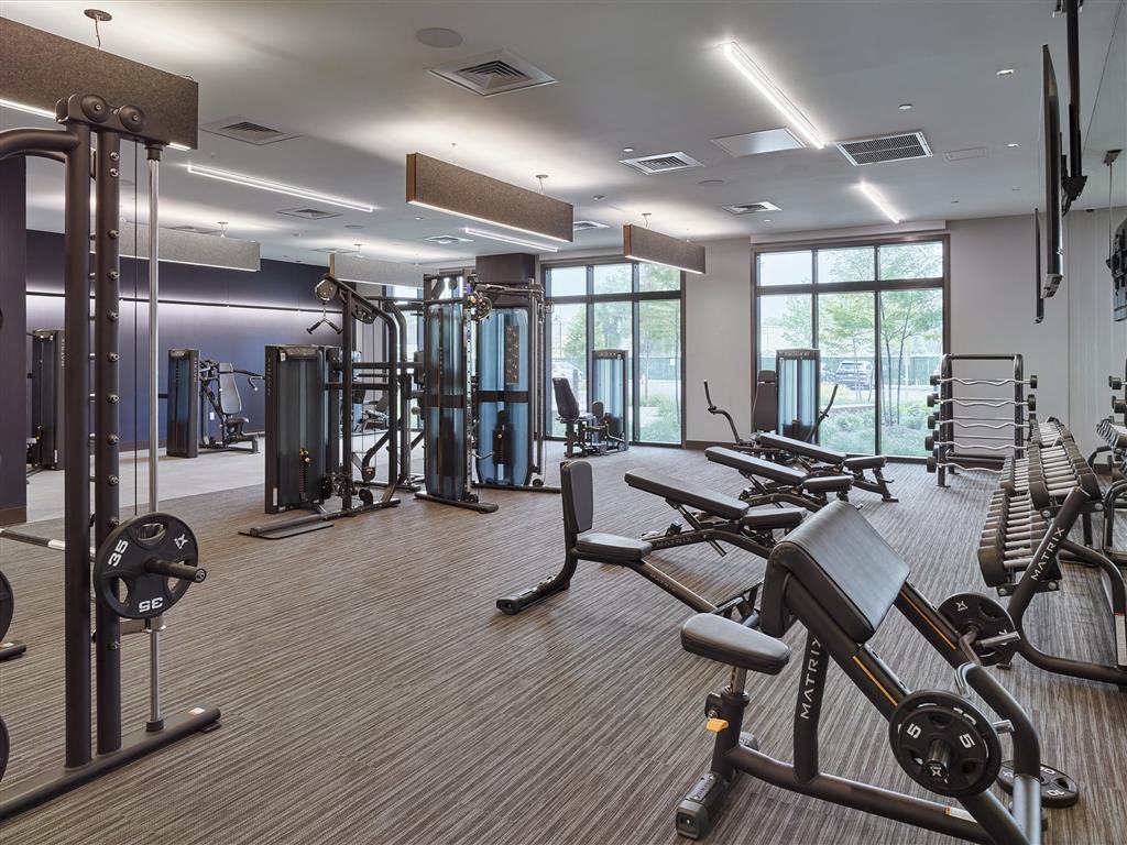 A gym with a variety of equipment including treadmills, weights, and exercise machines.