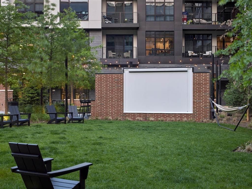 A white screen is mounted on a brick wall in a backyard.