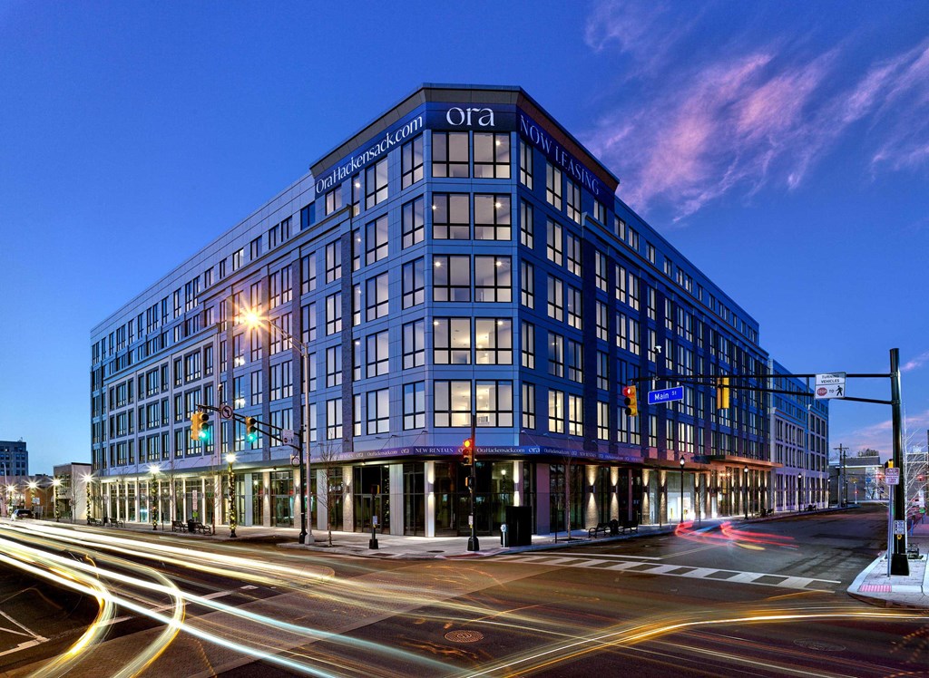 Evening exterior view of Ora luxury apartments featuring illuminated windows in Hackensack, NJ