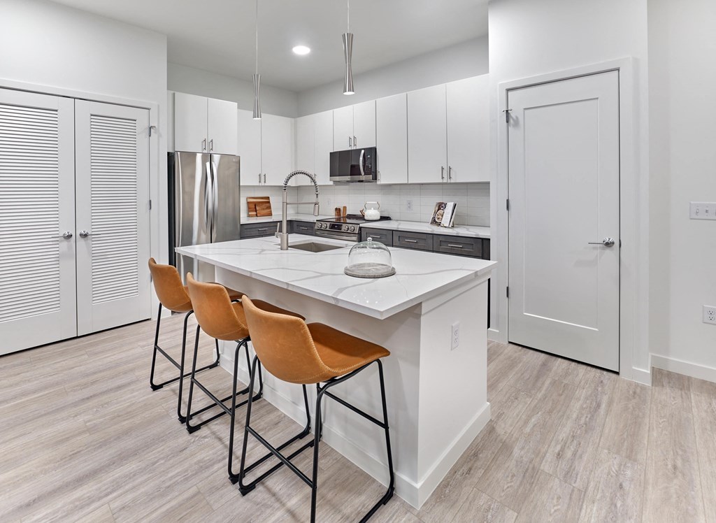 Modern kitchen with large island, bar seating, and stainless steel appliances at Ora in Hackensack, NJ