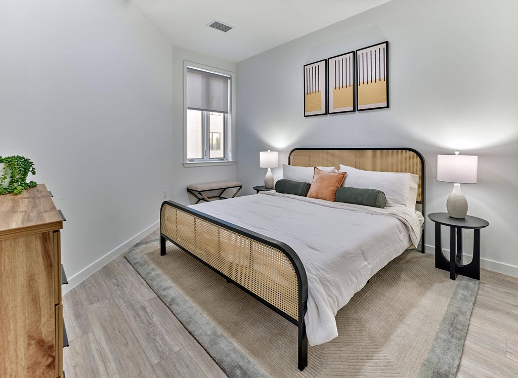 Bright bedroom with modern furnishings and bold accent art at Ora in Hackensack, NJ