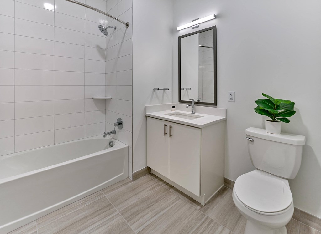 Bright bathroom with large mirror, single vanity, and modern tile design at Ora in Hackensack, NJ
